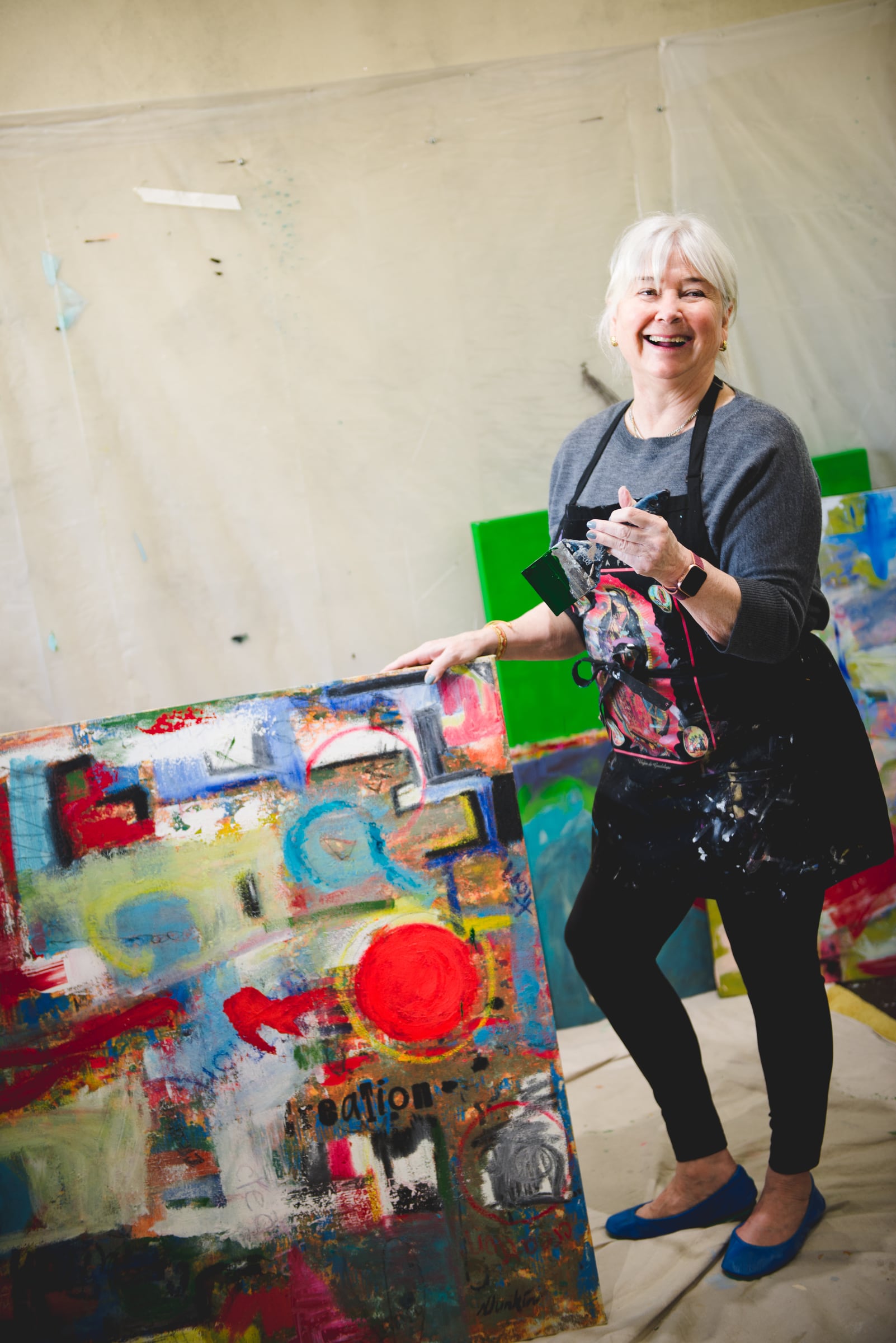 Nancy Junkin smiling beside a colorful painting